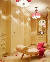 a cool warm-colored feminine closet with sleek storage units and drawers, a neutral printed daybed, touches of red – pendant lamps and a blanket