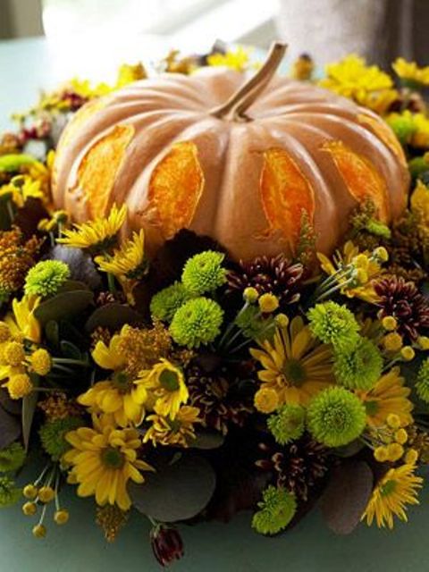 a bright fall centerpiece of a pumpkin with petals and super bright natural blooms and greenery wows