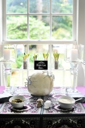 white candles, a white pumpkin decorated with a spider and white bowls are great to make your Halloween tablescape cooler