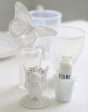 a stand with white candies, a white drink and a white butterfly are great for elegant and delicate Halloween styling
