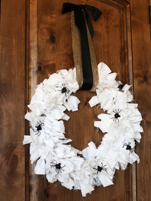 A white fabric strap Halloween wreath decorated with black spiders, with a burlap and black ribbon bow is a cool idea for Halloween