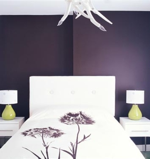 A purple bedroom with white furniture, table lamps with green bases and a quirky chandelier looks unique and statement like