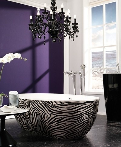 An exotic purple bathroom with a statement wall, a zebra print bathtub, a refined black chandelier and a black free standing sink