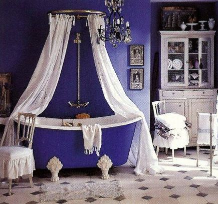 A vintage inspired purple and white bathroom with a mosaic tile floor, a canopy of curtains and a white buffet