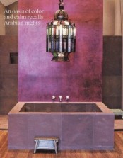 a Moroccan style bathroom done with purple tiles and bathtub plus a statement lantern