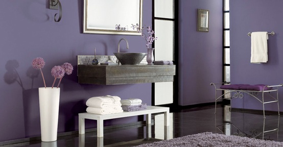 an eye-catchy purple bathroom with a dark tile floor, a floating wooden vanity and metallic touches
