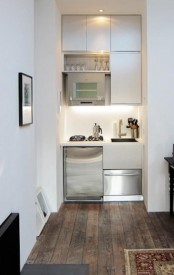 a very small minimalist kitchen with sleek cabinets, applainces built in and built-in lights