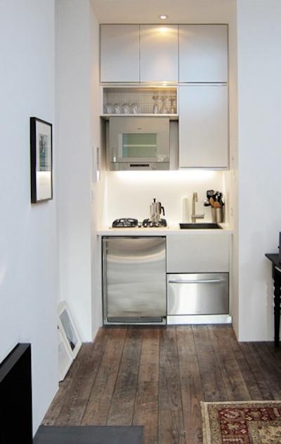 A very small minimalist kitchen with sleek cabinets, applainces built in and built in lights