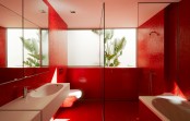 a minimalist red bathroom done with a large window and white appliances – a sink and a tub