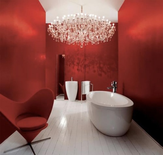 A refined red bathroom with a free standing sink and tub, a chic red chair and a statement crystal chandelier