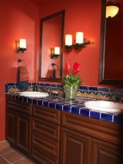 a red bathroom with stained wooden vanities, blue tiles and wall sconces looks bold and unique