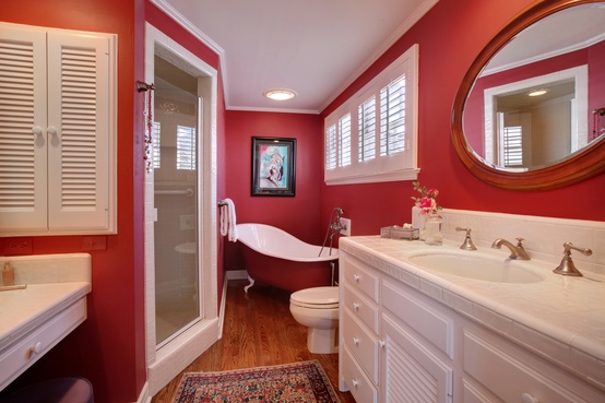 A small red bathroom with whites to refresh   a red and white bathtub, a white vanity and sinks plus a white shower space