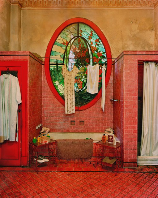 A whimsical bathroom with red tiles and buttercream walls, a mosaic window and a built in bathtub for a unique look