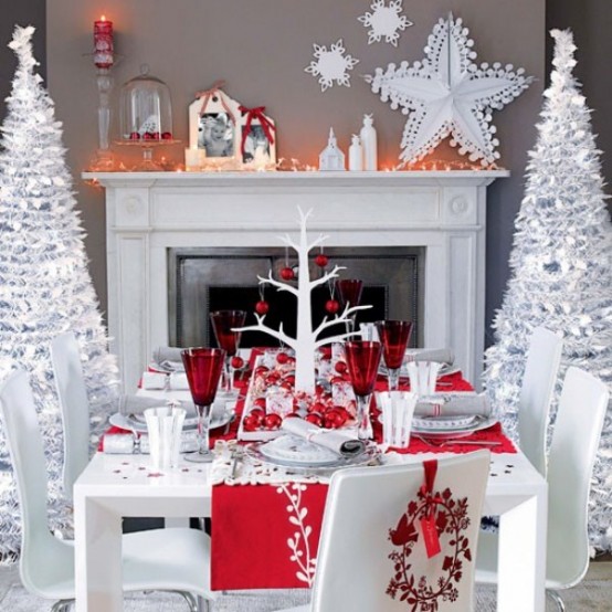 a contrasting red and white Christmas tablescape with red placemats, red glasses, a centerpiece of red ornaments and silver chargers
