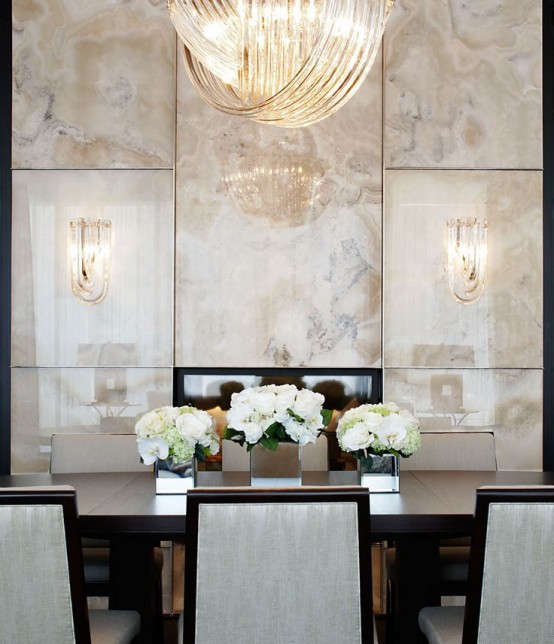 a formal sophisticated dining room with neutral onyx panels, a dark-stained dining table and neutral chairs, a large knot-like chandelier
