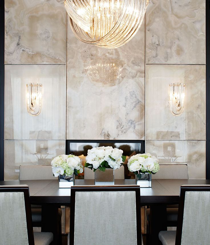 A formal sophisticated dining room with neutral onyx panels, a dark stained dining table and neutral chairs, a large knot like chandelier