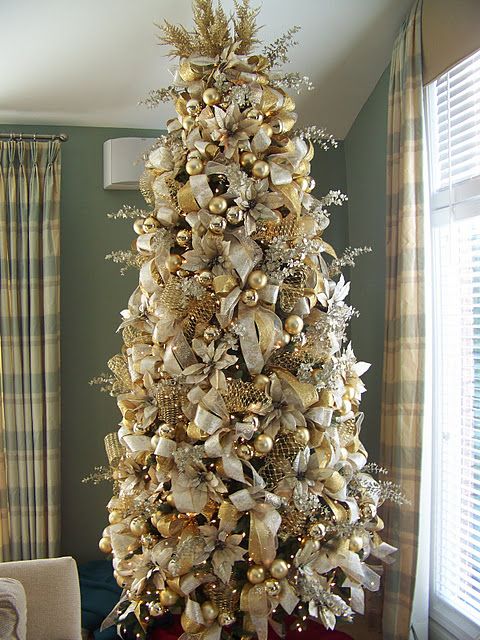 a super refined and glam Christmas tree masterpiece decorated with gold and white ornaments and ribbons, fabric blooms, mesh ribbons and branches