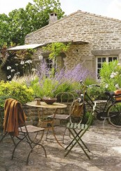 a small and lovely Provence terrace with a round table and metal chairs, greenery and lavender, a bike and a basket