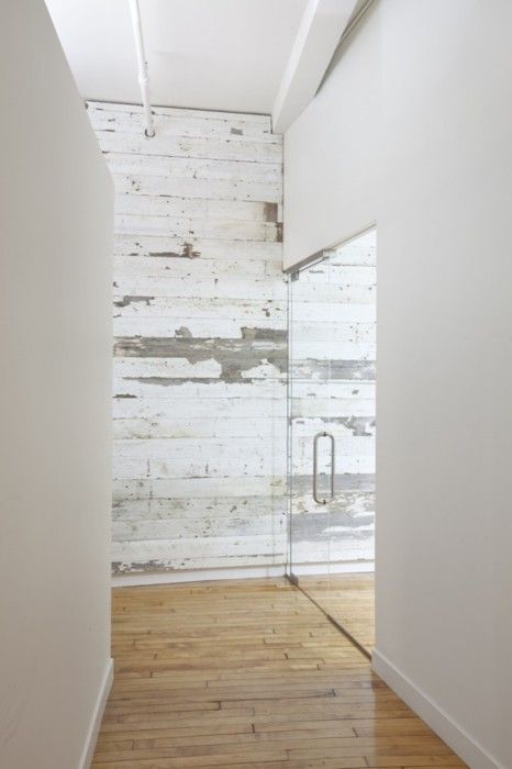 a minimalist space with a shabby chic whitewashed wall, sleek other walls and a glass door is wow
