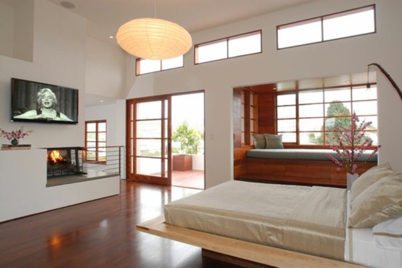 A neutral Japanese style zen bedroom with a wooden bed, a daybed by the windowsill, a built in fireplace and paper lamps