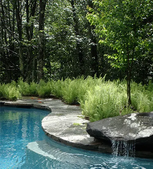 One large rock is more than enough for a beautiful waterfall by the pool.