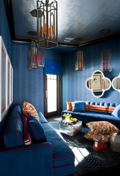 a bold blue living room done with pendant lamps and colorful pillows for an accent