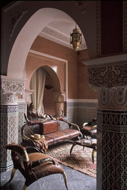 a Moroccan living room done in muted tones, with mosaic tile walls, traditional lanterns and carved furniture