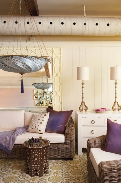 a neutral Moroccan living room spurced up with purple touches, carved and painted tables and pendant lamps