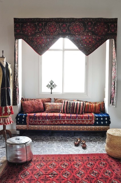 a neutral nook with a built-in sofa, colorful and patterned textiles and leather ottomans