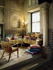 a gold Moroccan space with a super colorful L-shaped sofa and bright pillows, mosaic walls and beautiful chairs