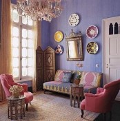 a colorful Moroccan living room with bright furniture, an ornate screen and decorative plates on the wall