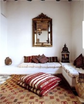 a neutral Moroccan living room with colorful and patterned pillows, a mirror and a lantern