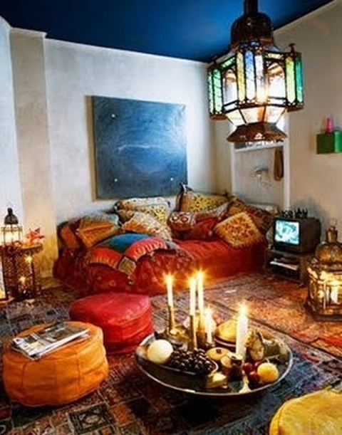 a colorful Moroccan living room with pillows, textiles, lanterns, candles and ottomans