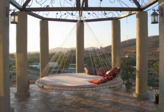 a round hanging bed with ropes and pillows hung in a gazebo is a great way to highlight this bed