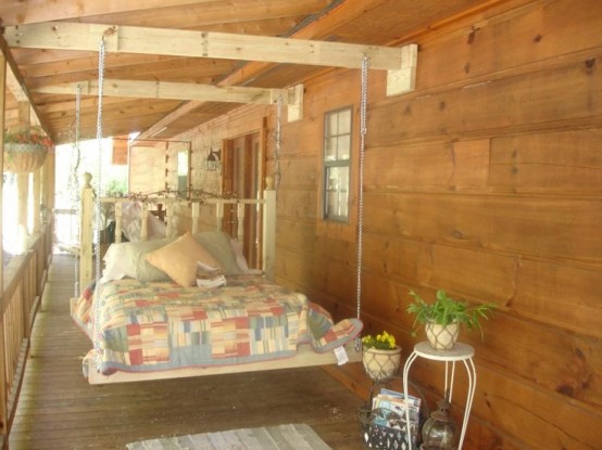 a hanging bed on chains on wooden beams will make your porch or patio super welcoming