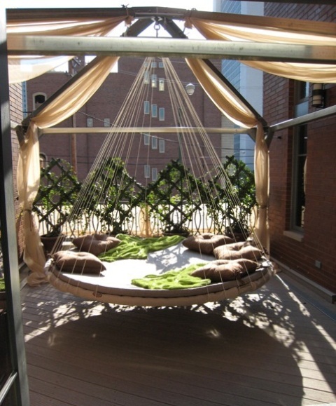 a round hanging bed on ropes with pillows and blankets makes up a gorgeous relaxing spot