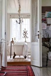 a shabby chic Scandinavian bathroom with a chandelier over the tub and vintage accessories