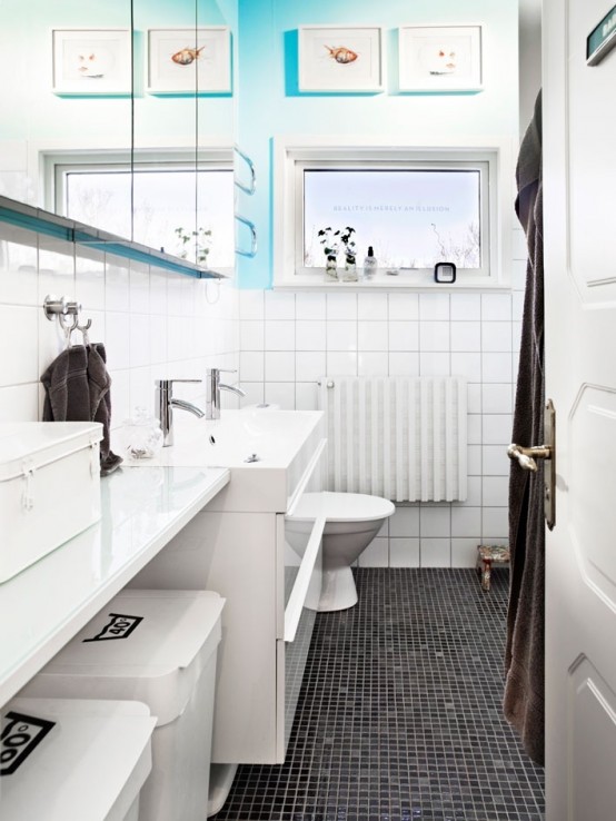 a black and white Scandi bathroom with a touch of blue and sea-inspired artworks