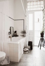 a vintage serene Scandinavian bathroom in white and grey, with vintage stools and potted greenery