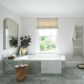 a grey and off-white Scandinaviann bathroom with Roman shades, a large mirror and a tree stump table