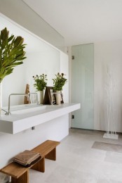a contemporary Scandinavian bathroom done in neutrals, with potted greenery and a wooden bench