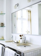 a simple Scandinavian bathroom with glass shelves, a stone countertop and white tiles