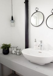 a fresh Nordic bathroom with a whitewashed wooden vanity, round mirrors and a bulb lamp