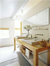 a welcoming Scandinavian bathroom with a wooden vanity, a large mirror and speckled sinks