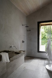 a minimalist Nordic bathroom done with concrete and stone tiles, stone sinks and a large window