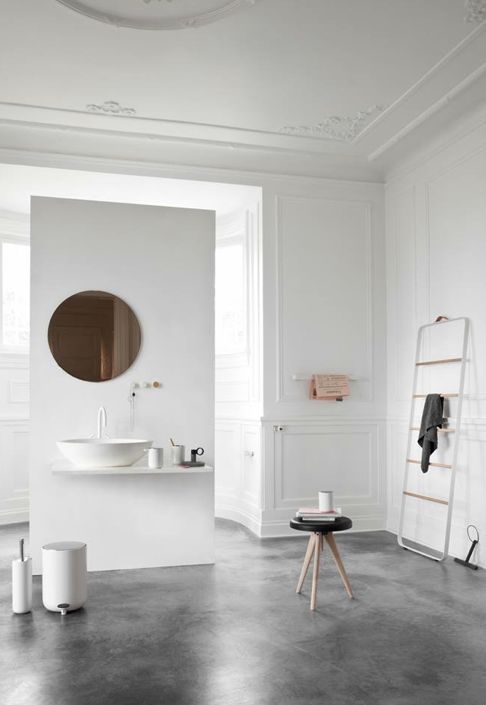a Scandinavian bathroom with a floating vanity, a copper mirror and some modern furniture