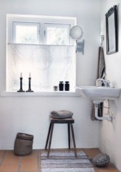 a white Nordic bathroom with a vintage feel, cadnles, mirrors and lamps plus and a basket for storage