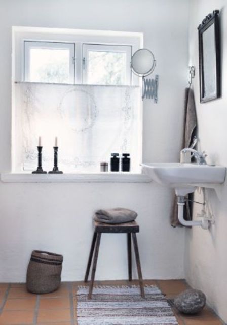 a white Nordic bathroom with a vintage feel, cadnles, mirrors and lamps plus and a basket for storage