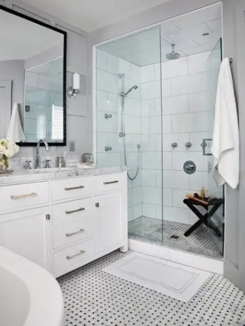 a serene white bathroom with a mosaic tile floor, a vanity with a neutral countertop and a glazed shower space