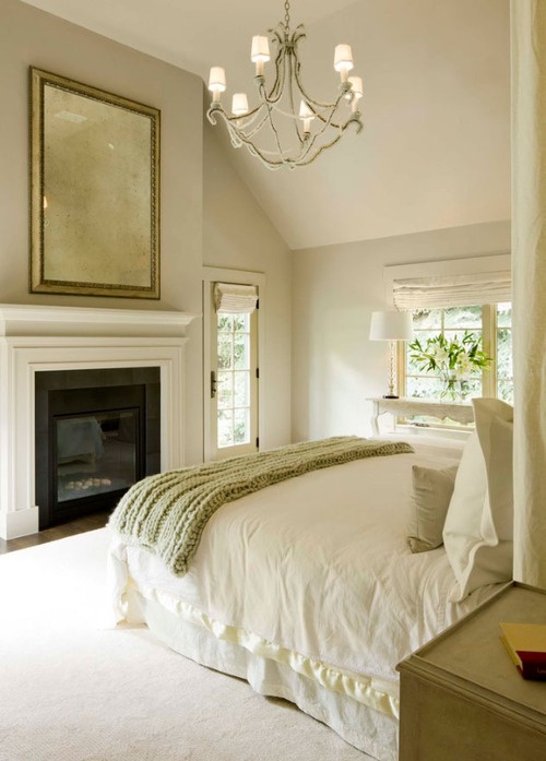 A warm colored neutral bedroom with a fireplace, an oversized fireplace, a bed and a vintage bedroom